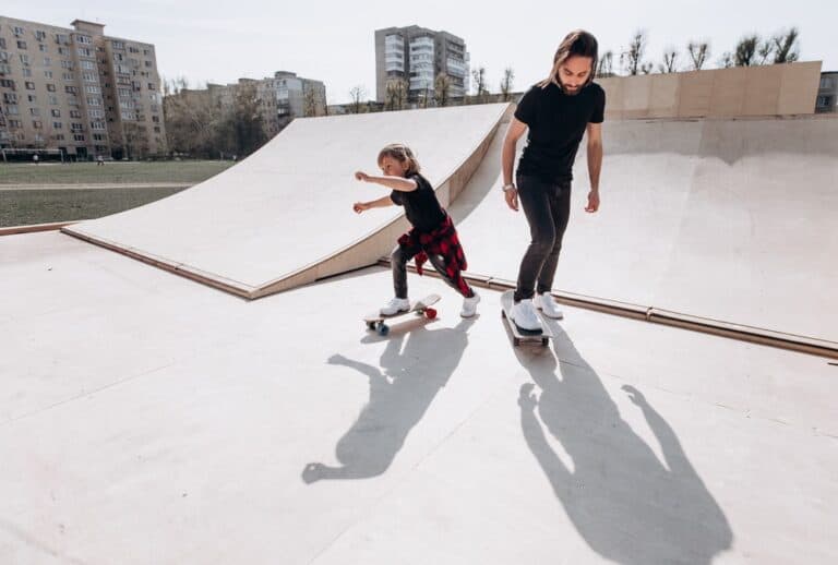 father teaching son to skateboard at skate park