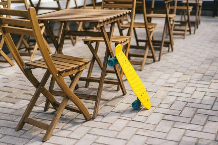 penny board leaning up against outdoor furniture table