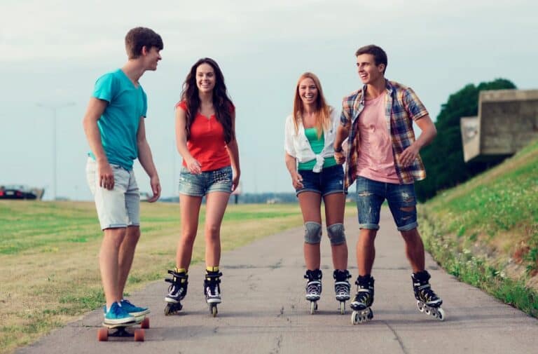 teenage friends skateboarding and rollerblading on the pavement