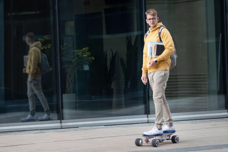 college student on campus using an electric skateboard
