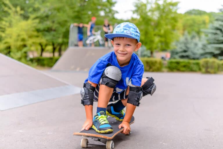 young boy standing on skateboard at skate park