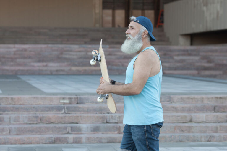 old man holding a skateboard at skate park