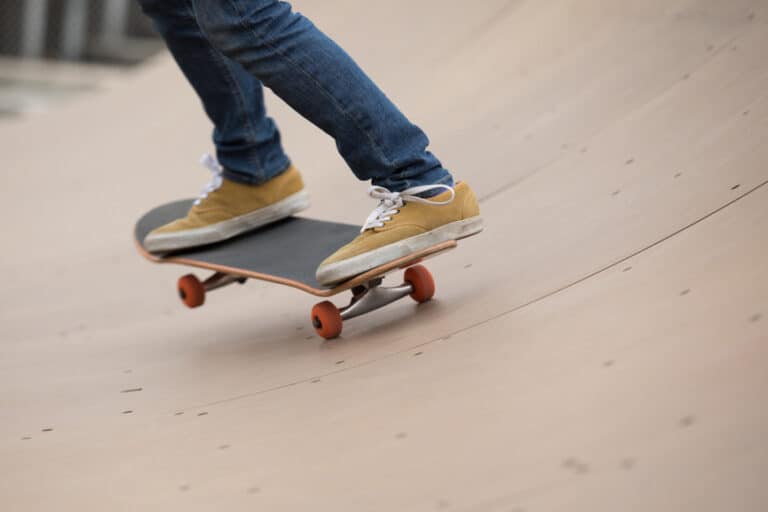 closeup of man standing on skateboard on skate ramp